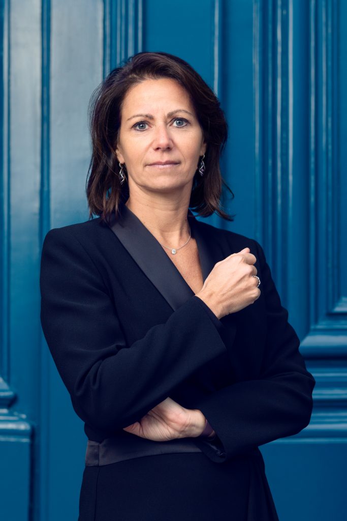 Sandra Lillaz, experte en formation vente dans le luxe et la joaillerie, associée à Guillaume Duprat, devant une porte bleue emblématique de la Place Vendôme